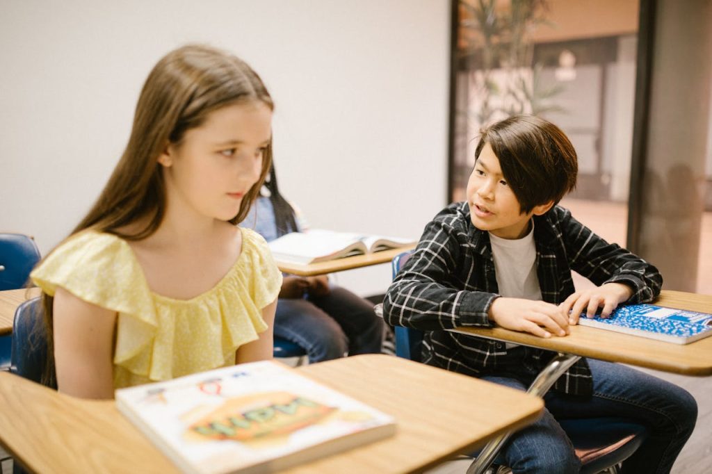 Two students in a classroom interacting with each other during a lesson.